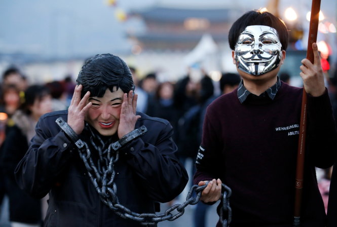 Người biểu tình đeo mặt nạ bà Park (trái) đòi bắt giữ đưa Tổng thống bị phế truất ra tòa. Người dân tiếp tục biểu tình tại Seoul ngày 11-3 - Ảnh: Reuters 