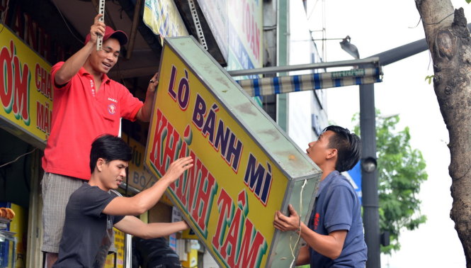 Người dân trên đường Lý Thái Tổ tháo dỡ bảng hiệu trả lại không gian cho vỉa hè - Ảnh: Lê Phan