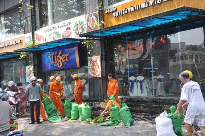 Lực lượng chức năng quận 5 dọn một bồn hoa trên vỉa hè trước một nhà hàng ở đường Nguyễn Văn Cừ - Ảnh: NGỌC HÀ