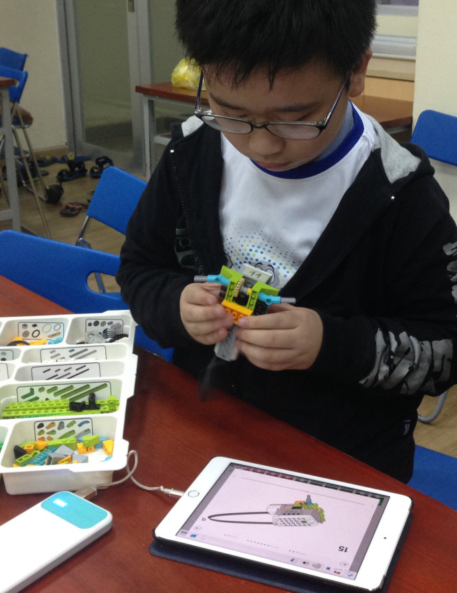 Em Kim Bubin (10 tuổi) đang tháo dỡ mô hình để xem lại các chi tiết trong robot - Ảnh: Lê Đinh