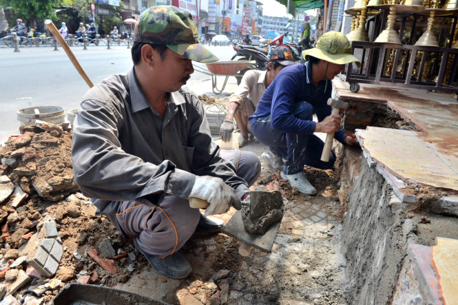 Nhiều nhà dân tại đường Bạch Đằng (quận Bình Thạnh) thuê người tháo dỡ các bục dẫn xây lấn vỉa hè - Ảnh: Lê Phan
