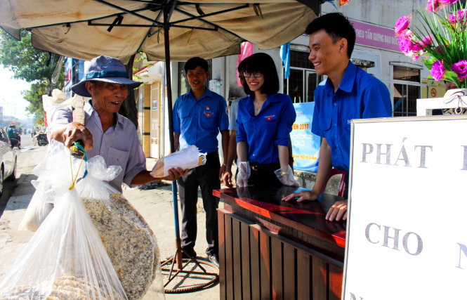 Ông Phạm Văn Bé (bán hàng rong) nở nụ cười tươi rói khi nhận ổ bánh mì miễn phí - Ảnh: Thái Thịnh