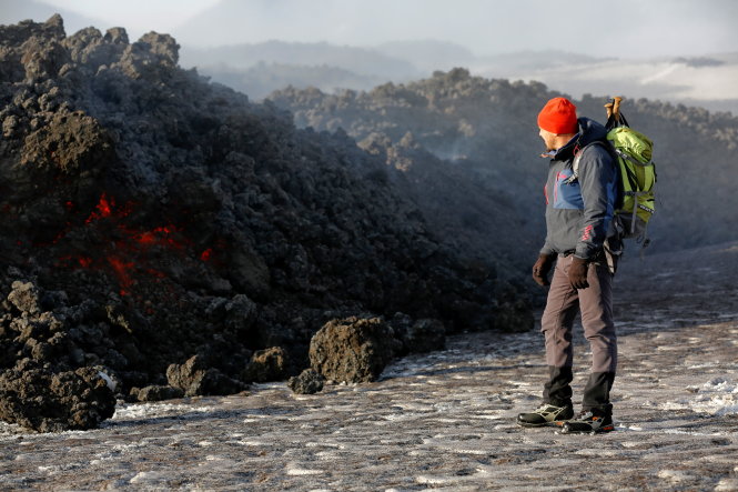 Hướng dẫn viên núi lửa tiếp cận gần dòng dung nham của Etna - Ảnh: Reuters
