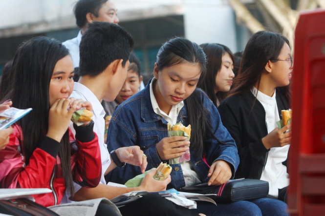 Nhiều học sinh đi sớm, không kịp ăn sáng nên vội mua bánh mì để lót dạ ngay tại nơi diễn ra buổi tư vấn tuyển sinh hướng nghiệp trong khuôn viên Trường đại học Đồng Tháp - Ảnh: Chí Quốc