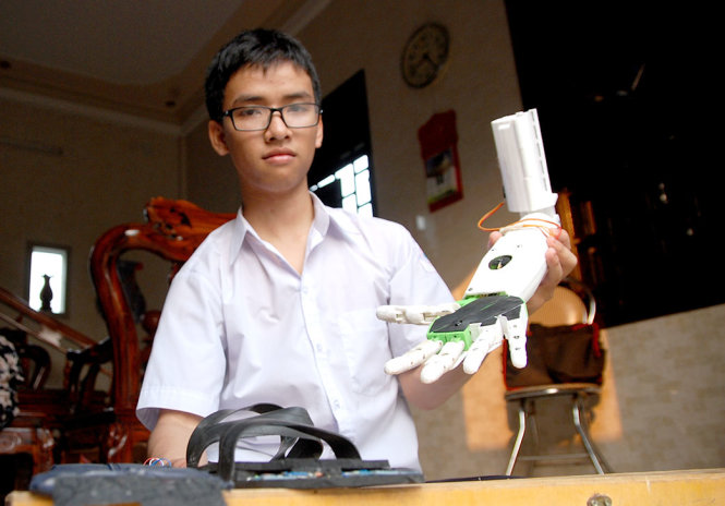 Huy thử nghiệm khả năng vận hành co duỗi các ngón tay của cánh tay robot do mình chế tạo – Ảnh: QUỐC NAM