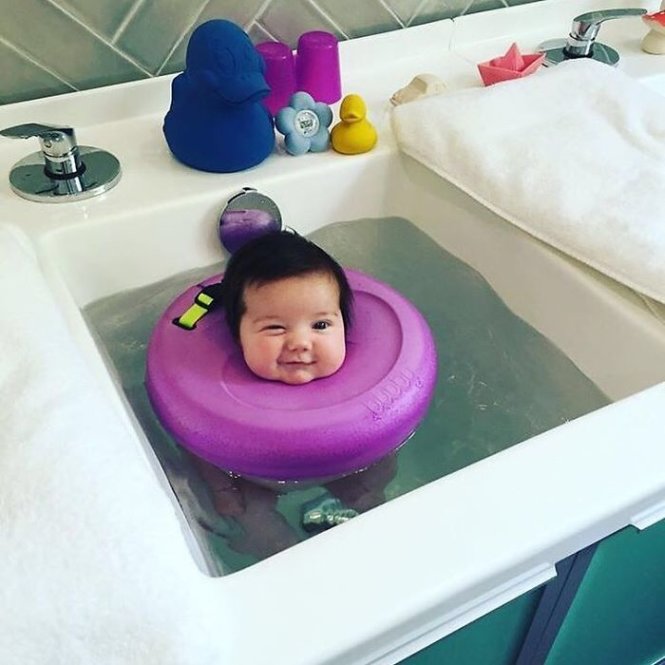 Một em bé cười tít mắt khi xuống nước