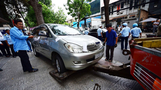 Một xe ôtô đậu trên vỉa hè bị niêm phong cẩu về xử lý - Ảnh: Hữu Thuận