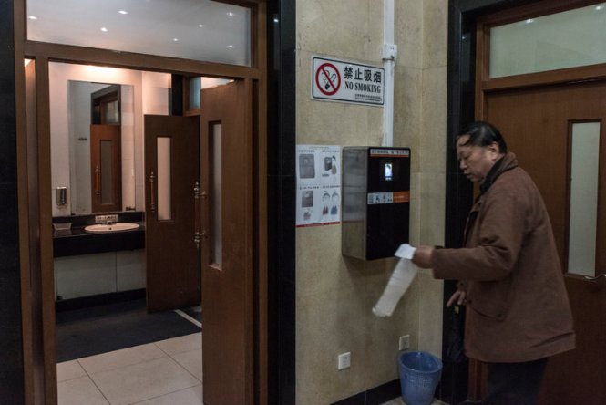 Một du khách sử dụng máy cấp giấy vệ sinh tích hợp công nghệ nhận diện khuôn mặt tại công viên Thiên Đàn ở Bắc Kinh, Trung Quốc - Ảnh: New York Times