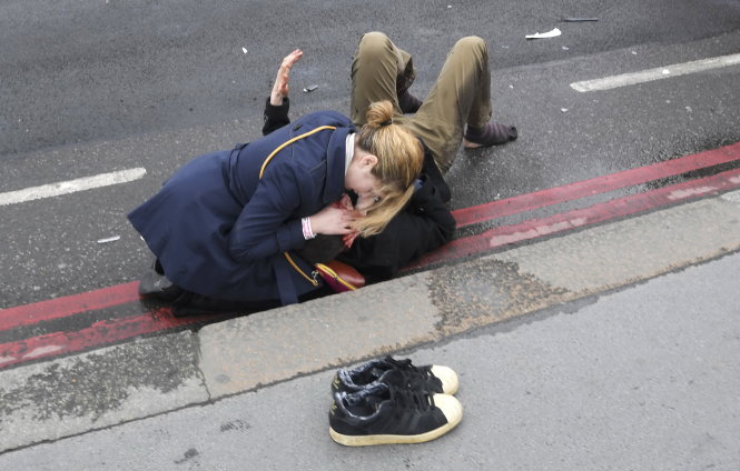 Nữ cảnh sát Anh hỗ trợ một người bị thương tại hiện trường - Ảnh: Reuters