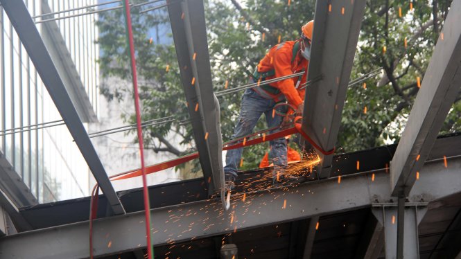 Công nhân dùng đèn khò gió đá để cắt khung sắt, mái che - công trình vi phạm của tòa nhà SaiGon Center - Ảnh Q.Khải