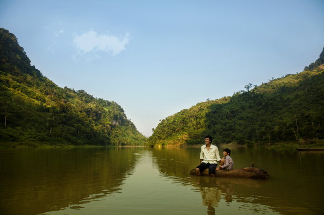 Nhân vật cha (diễn viên Ngô Thế Quân) và con (Đỗ Trọng Tấn đến từ làng trẻ em SOS) trên khúc gỗ nổi trong phim - Ảnh: ĐPCC