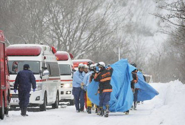 Đội cứu hộ đưa người bị thương ra ngoài - Ảnh: Kyodo News