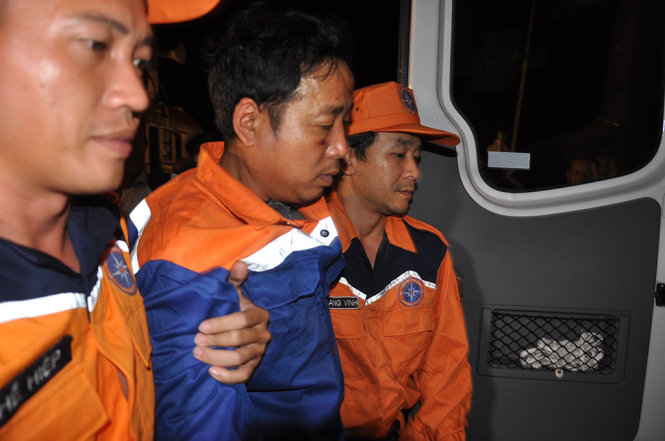 Thuyền trưởng Nguyễn Viết Thắng (người đi giữa) được dìu ra xe cấp cứu, sau khi về bờ - Ảnh: ĐÔNG HÀ