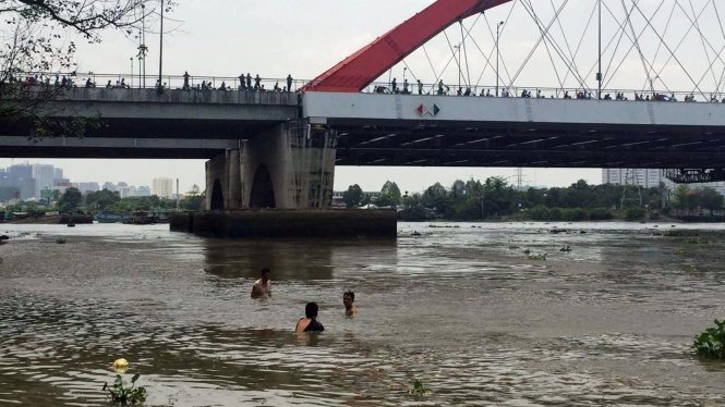 Nhiều người tham gia lặn tìm thi thể bé trai bị nước cuốn trên sông Sài Gòn - Ảnh: Lê Phan