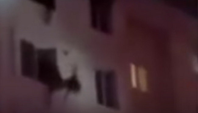 Người phụ nữ rớt khỏi cửa sổ khi tìm cách thoát khỏi đám cháy - Ảnh chụp từ clip