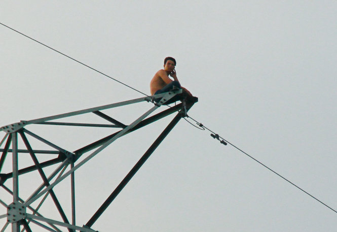 Người đàn ông leo cột điện cao thế cao hơn 50 mét vào gày 25-3 - Ảnh: XUÂN AN