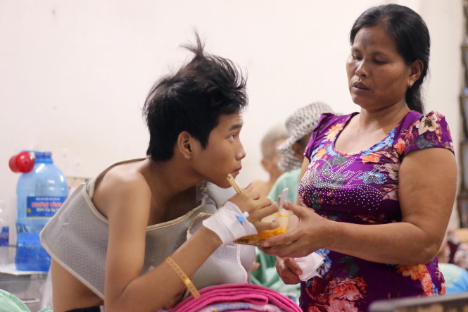 Bà Danh Thị Quươl chăm sóc con trai 16 tuổi Danh Trần Thái tại Bệnh viện Chấn thương chỉnh hình TP.HCM - Ảnh: NGỌC HIỂN