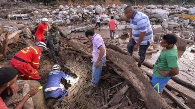 Lực lượng cứu hộ tìm kiếm người bị mắc kẹt dưới đống đổ nát và cây ngã - Ảnh: AFP