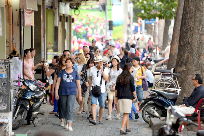 Người dân và du khách nước ngoài đi bộ trên vỉa hè đường Lê Lợi, quận 1 (TP.HCM) - Ảnh: HỮU KHOA