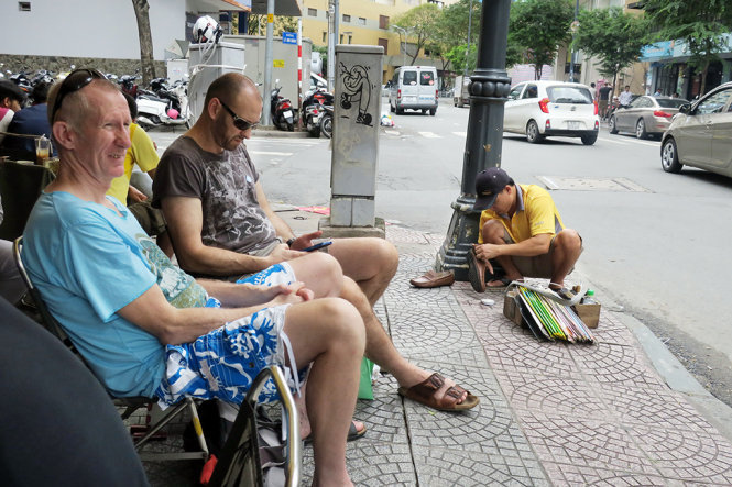 Du khách nước ngoài thích thú ngồi vỉa hè, uống cà phê, uống trà ngắm phố phường trung tâm Sài Gòn - Ảnh: T.T.D.