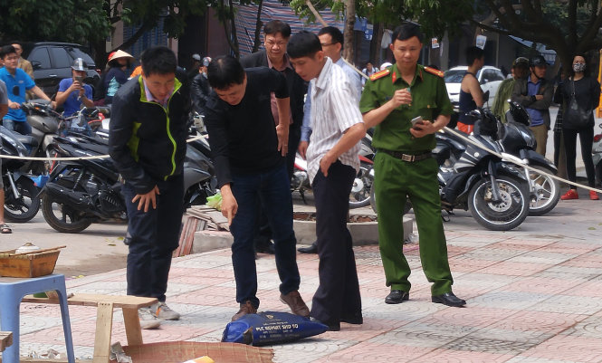 Nắp thùng phuy (màu xanh) bị bẻ cong tại điểm nạn nhân ngồi ngoài tòa nhà - Ảnh: TIẾN THẮNG