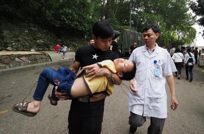 Một đứa trẻ bị ngất đang được người thân đưa khỏi đền Hùng để chăm sóc -
 - Ảnh: Nguyễn Khánh