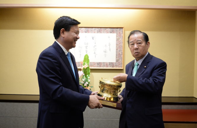 Ông Toshihiro Nikai – Tổng thư ký đảng LDP thử tiếng kêu phát ra từ chiếc trống đồng mà đoàn đại biểu cấp cao TP.HCM tặng - Ảnh: THUẬN THẮNG