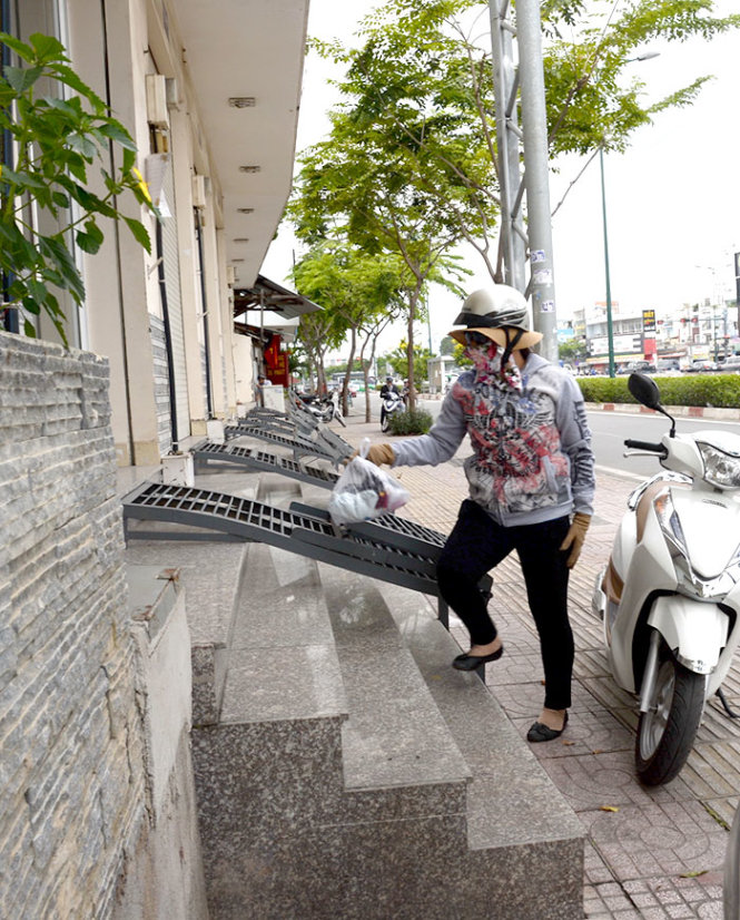 Nhà cao hơn vỉa hè đường Phạm Văn Đồng (phường 1, quận Gò Vấp) gần 1m nên người dân phải xây bậc và lắp thêm những tấm sắt để ra vào nhà  Ảnh: TỰ TRUNG