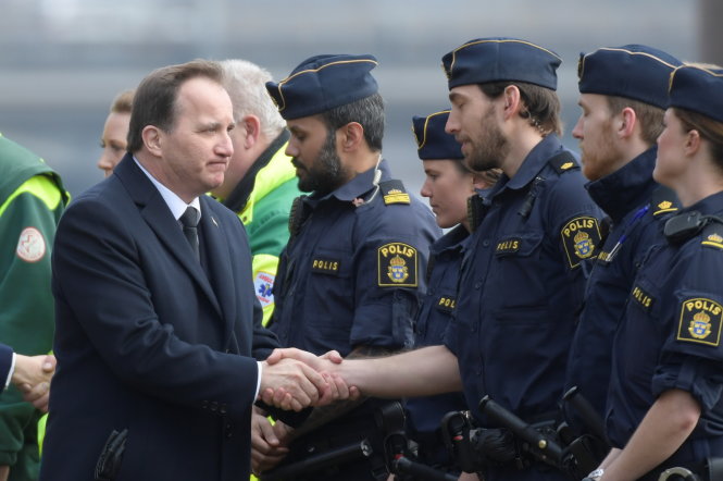 Thủ tướng Thụy Điển Stefan Lofven bắt tay lực lượng bảo vệ an ninh ở thủ đô Stockholm trong buổi lễ tưởng niệm trưa 10-4 - Ảnh: Reuters