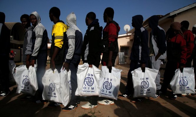 Những người di cư Gambia từ Libya trở về nhà, mang theo những túi đồ hỗ trợ của IOM - Ảnh: Reuters