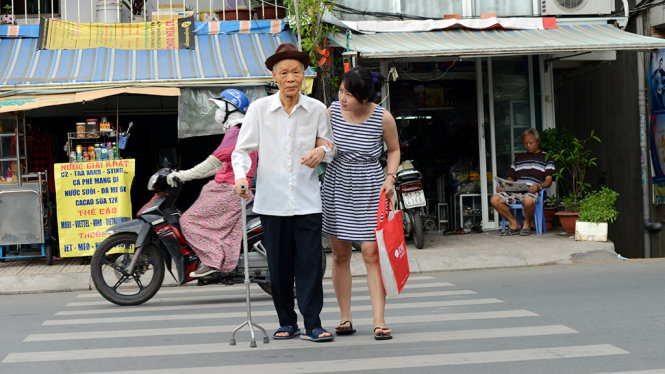 Cụ Trương Văn Lương (90 tuổi) được một bạn trẻ dắt qua đường Xô Viết Nghệ Tĩnh (Q.Bình Thạnh, TP.HCM) - Ảnh: DUYÊN PHAN