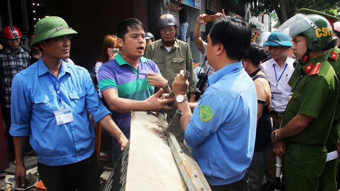 Trong quá trình cưỡng chế, giải tỏa hành lang an toàn giao thông, trật tự đô thị, một số hộ dân đòi lấy lại tấm biển quảng cáo đã bị tháo dỡ - Ảnh: DOÃN HÒA