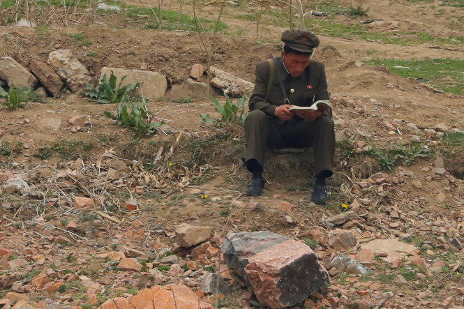 Một binh sĩ Triều Tiên ngồi đọc sách trên bờ sông Áp Lục, ranh giới Trung - Triều ngày 16-4 - Ảnh: Reuters
