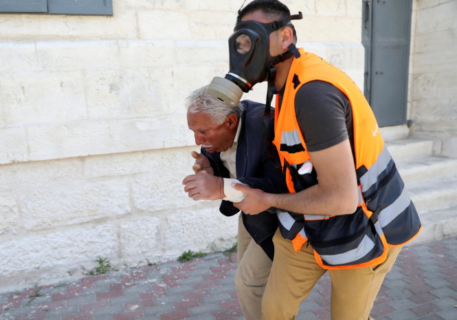 Một người Palestine lớn tuổi được hỗ trợ sau khi trúng khói đạn cay - Ảnh: Reuters