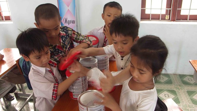 Một nhóm bạn cùng lớp 1A Trường tiểu học Quảng Phương B săm soi hộp sữa ngay trong lớp học