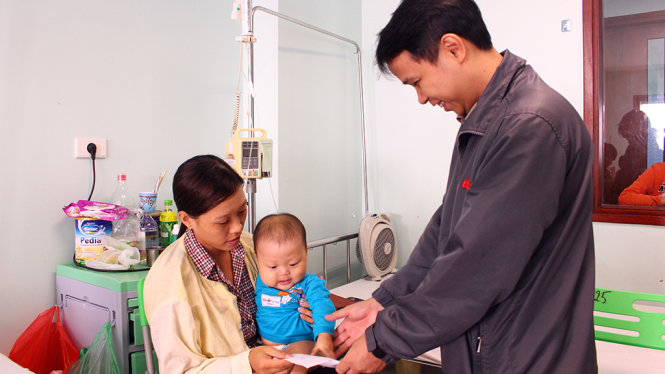 Đại diện báo Tuổi Trẻ (bìa phải) trao giấy chứng nhận đóng tạm ứng viện phí cho phụ huynh các bệnh nhi tại Hà Nội - Ảnh: HÀ THANH