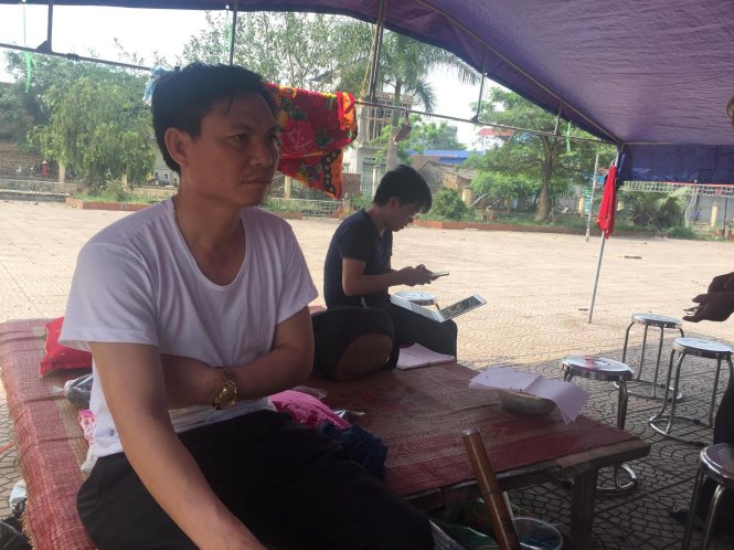 Ông Cảnh được đưa ra khỏi khu vực tạm giữ và đang ngồi trong lều dựng bên cạnh nhà văn hoá - Ảnh: Thân Hoàng