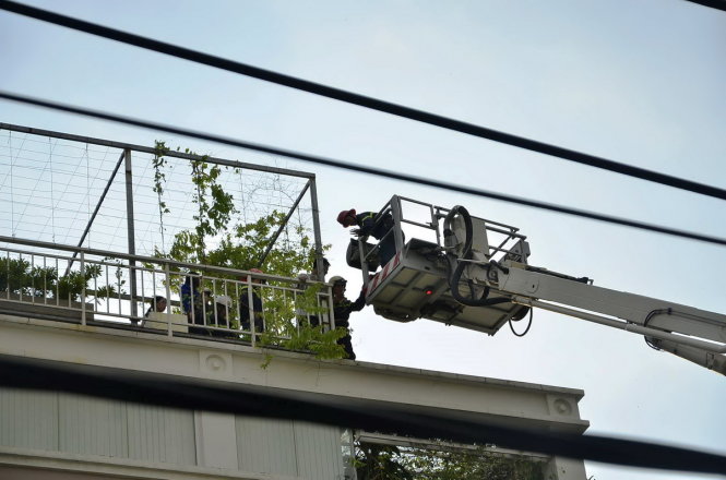 Lực lượng chức năng dùng xe thang giải cứu người mắc kẹt trên sân thượng xuống đất - Ảnh: TÂM ĐỨC