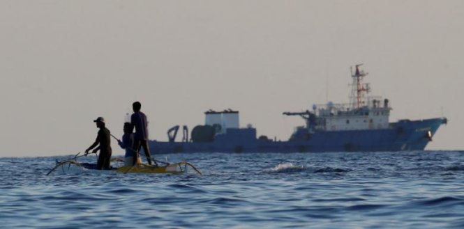 Các ngư dân Philippines đang đi qua một chiếc tàu lớn của Trung Quốc ở khu vực bãi cạn Scarborough ngày 15-4-2017 - Ảnh: Reuters
