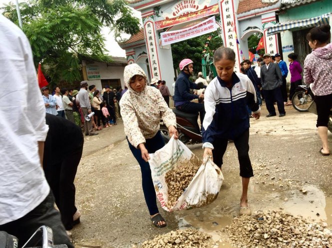 Người dân dọn dẹp chướng ngại vật trước cổng làng - Ảnh: NGUYỄN KHÁNH