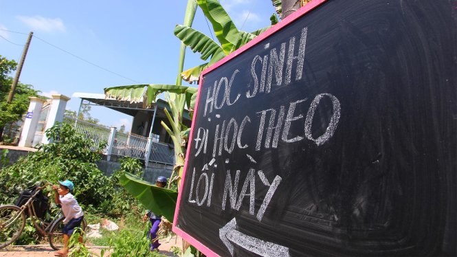 Học sinh Trường tiểu học “A” Mỹ Hội Đông phải đi theo lối mới ở cổng sau vì cổng chính đã bị phong tỏa - Ảnh: Chí Quốc