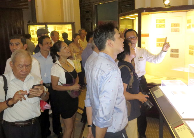 Ông Hoàng Anh Tuấn (bìa phải) đang giới thiệu triển lãm với khách tham quan tại buổi khai mạc - Ảnh: L.Điền