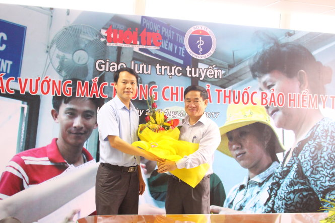 Ông Hồ Thanh Vinh, phó trưởng văn phòng đại diện báo Tuổi Trẻ tại miền Bắc (trái), tặng hoa ông Hà Văn Thúy, phó vụ trưởng Vụ Bảo hiểm y tế, Bộ Y tế - Ảnh: Hà Thanh