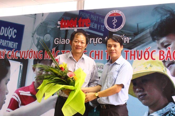 Ông Hồ Thanh Vinh, phó trưởng văn phòng đại diện báo Tuổi Trẻ tại miền Bắc (phải), tặng hoa ông Dương Đức Hùng, Trưởng phòng Kế hoạch - Tổng hợp, Bệnh viện Bạch Mai - Ảnh: Hà Thanh