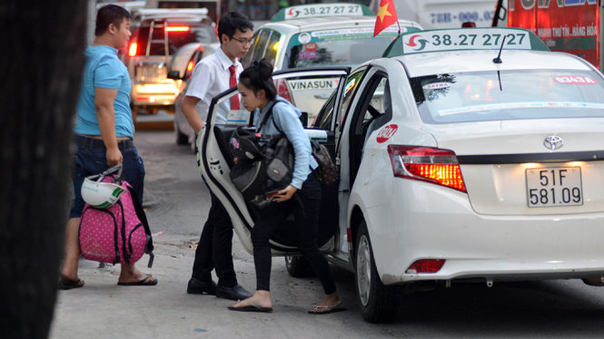 Hai khách đi taxi xuống xe đi bộ vào bến xe do phía trước dòng xe bị ùn ứ - Ảnh: Lê Phan