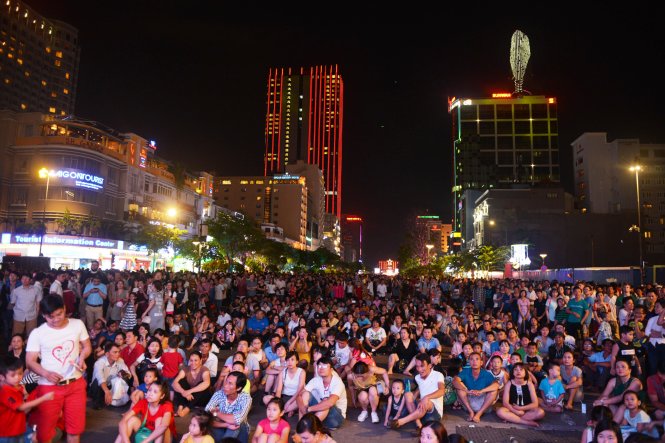 Hàng ngàn người dân ngồi trên phố đi bộ Nguyễn Huệ để theo dõi buổi biểu diễn qua các màn hình gắn bên ngoài sân khấu - Ảnh: Lê Phan