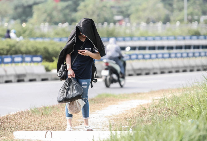 Bạn nữ dùng áo khoách choàng lên người trong lúc đợi xe trên đường Trần Duy Hưng - Ảnh: NAM TRẦN