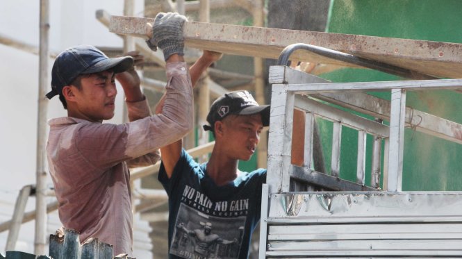 Hai nam lao động ướt sũng mồ hôi làm việc giữa nắng nóng trưa 2-5 tại một công trình xây dựng ở gần chợ Vinh - Ảnh: Doãn Hòa