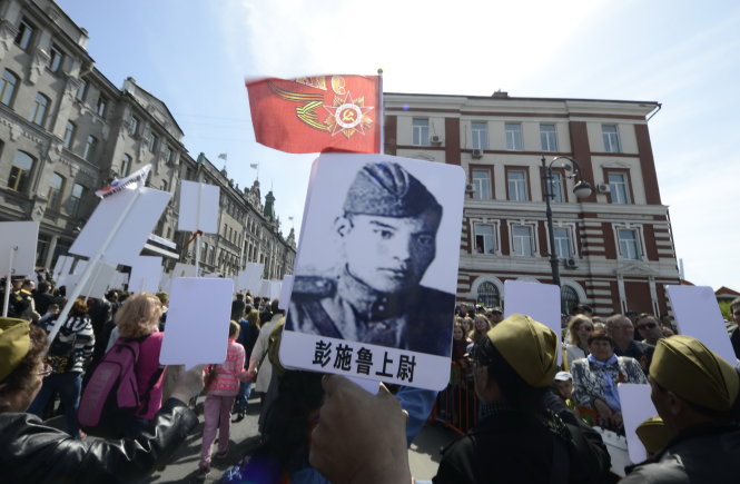 Người dân đem theo hình ảnh cha ông từng hi sinh trong Thế chiến II tại cuộc diễu hành của 