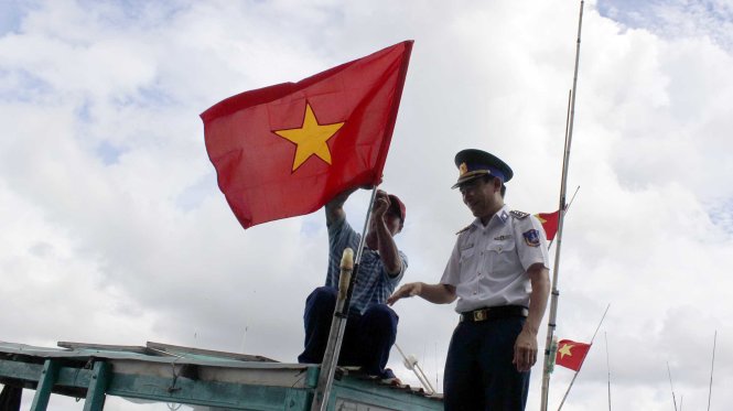 Cảnh sát biển thay lá cờ Tổ quốc mới cho tàu cá của ngư dân tại cảng Cát Lở sáng 10-5 - Ảnh: Đông Hà